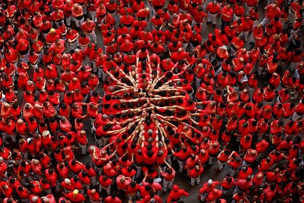 Group members of "Colla Joves Xiquets de Valls" start their human tower formation called a "castell" during the biannual human tower competition in Tarragona, Spain