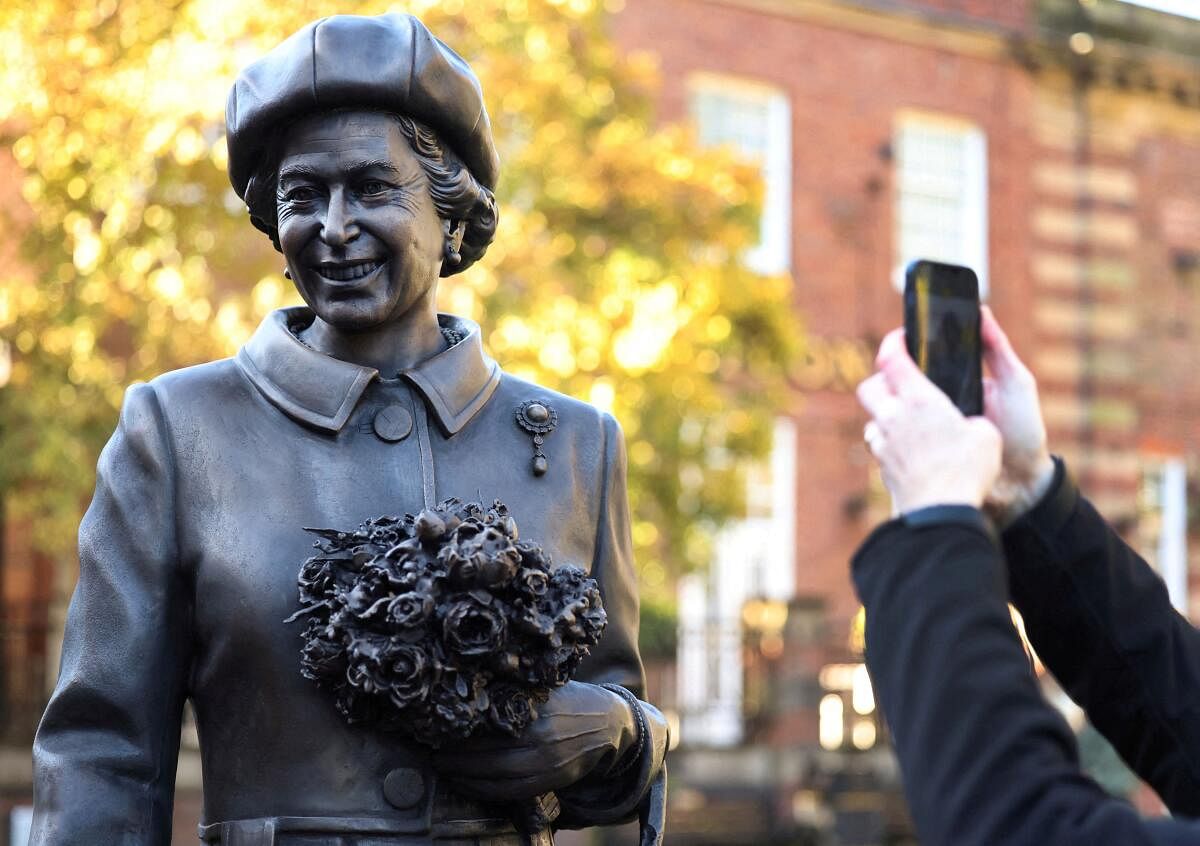 A man takes a photograph of a new statue of late Britain's Queen Elizabeth by artist Andy Edwards in Newcastle-under-Lyme.