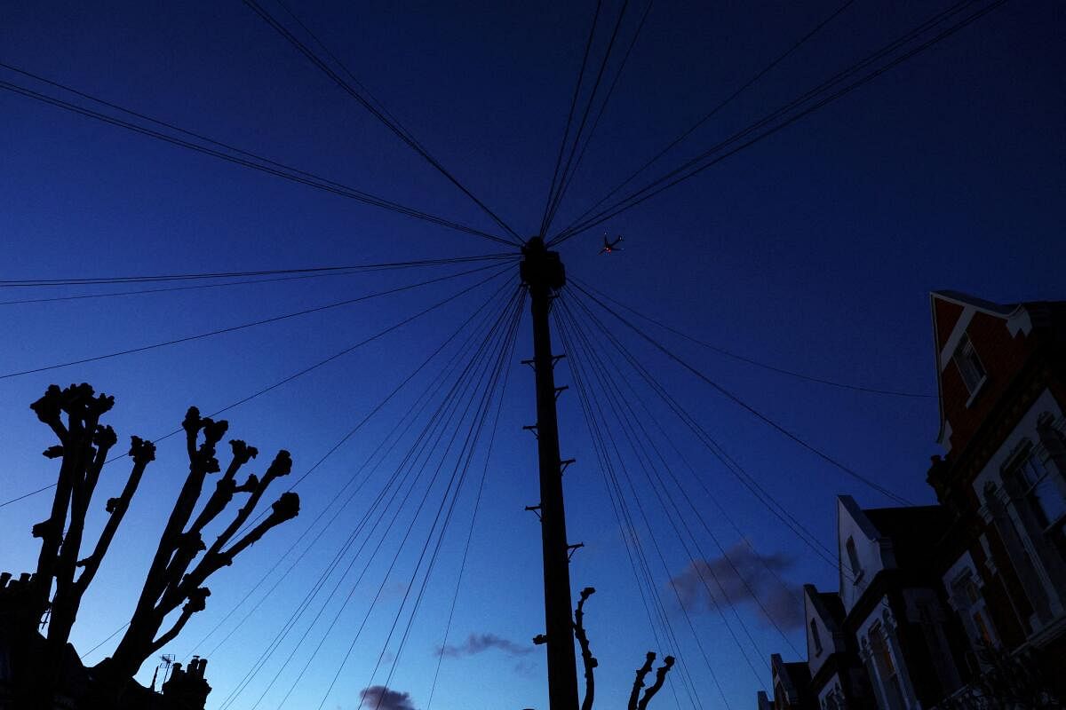 An airplane descends to London Heathrow Airport above telephone lines in London, Britain.