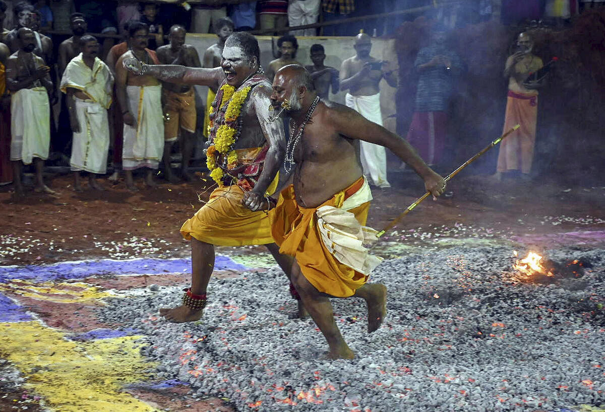 Devotees walk through a pit of burning wood during the 'Agni Kavadi' rituals at the Pournamikavu temple, in Thiruvananthapuram.