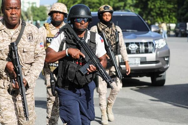 Security personnel escort the car of a member of Haiti's presidential council as they arrive for an event marking the 218 anniversary of the killing of national independence hero Jean-Jacques Dessalines, in Port-au-Prince, Haiti.