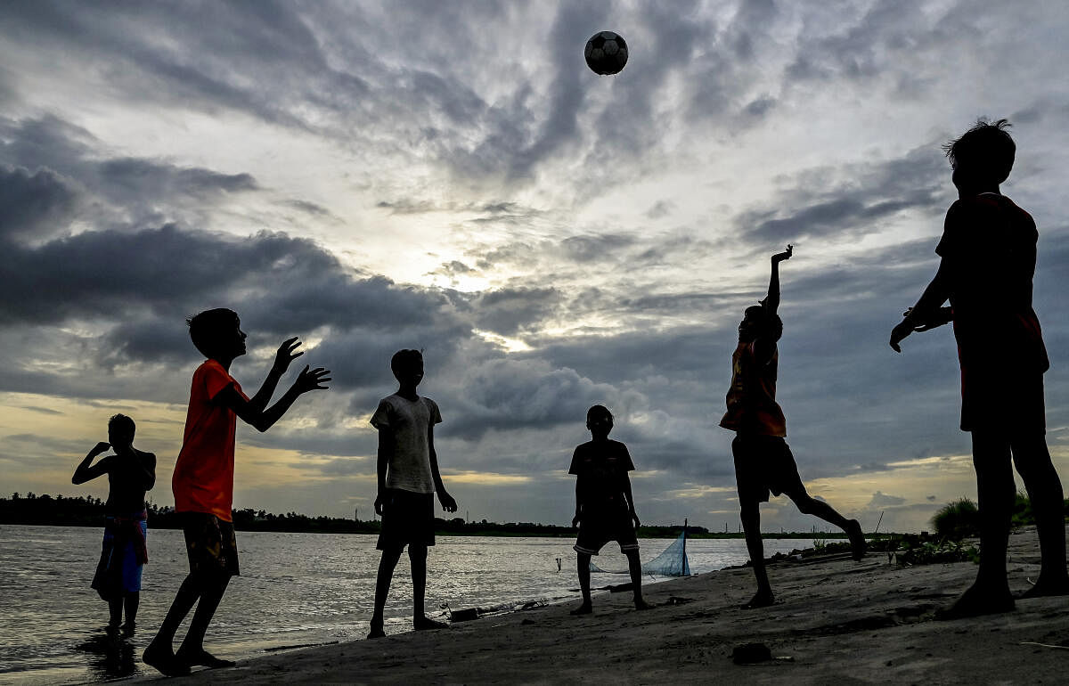 Boys at play at the bank of the Hooghly river under a cloudy sky, in Nadia.