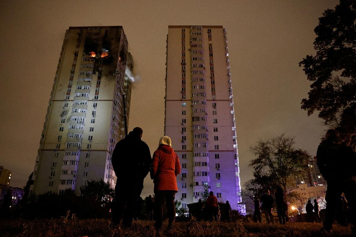 People watch a fire in an apartment building that was damaged during a Russian drone strike, amid Russia's attack on Ukraine, in Kyiv, Ukraine,