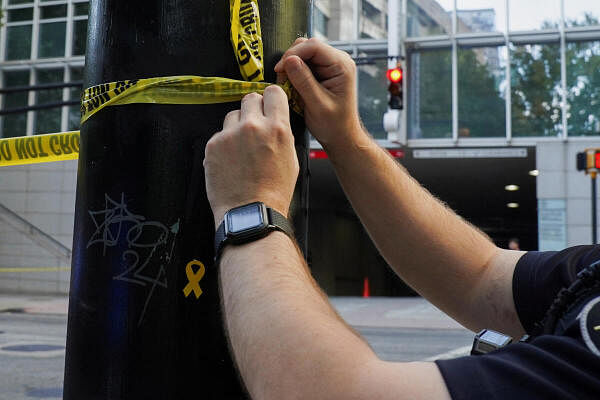 An officer ties up a police line on a pole with a yellow ribbon on it, after police responded to reports of a man shooting a firearm at the Four Seasons Hotel in Atlanta, Georgia.