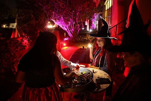 Residents dressed like witches look on as kids go trick-or-treating by a decorated house on Halloween night in Pasadena, California, US.