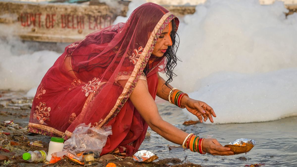 A devotee performs rituals on the bank of the Yamuna river as toxic foam floats on the surface of the polluted river during the start of the 4-day Chhath Puja festival, at Kalindi Kunj in New Delhi.