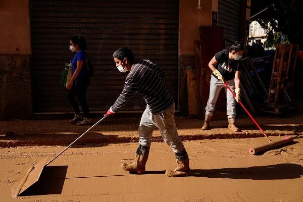 Volunteers and local residents sweep mud from a road caused by heavy rain in Paiporta, near Valencia, Spain, on November 5, 2024.