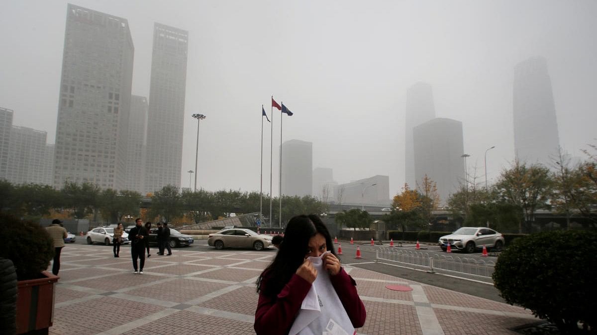 File Photo: A woman covers her nose as she walks in the central business district on a polluted day after a yellow alert was issued for smog, in Beijing, China. 