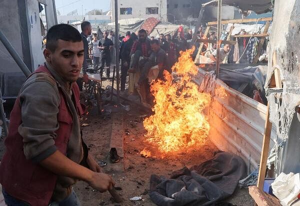 People carry a casualty near a fire at the site of an Israeli strike on a tent housing displaced people, at Al-Aqsa Martyrs Hospital in Deir Al-Balah, in the central Gaza Strip.