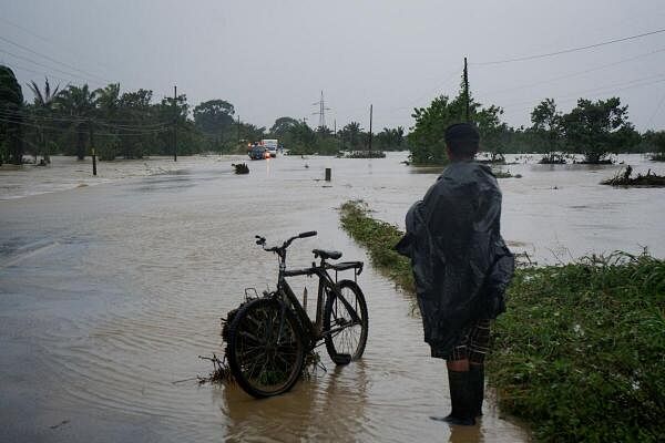 A man stands next to his bicycle on a flooded road after the Arizona River overflowed its banks due to heavy rain brought by Tropical Storm Sara, in Tela, Honduras November 15, 2024.