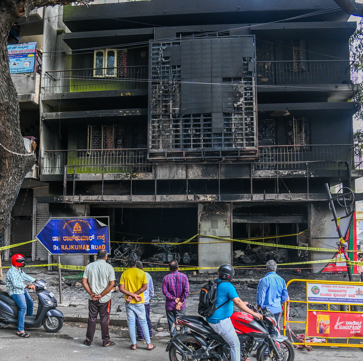 People gather outside the EV scooter showroom that was gutted on Rajkumar Road in Rajajinagar on Wednesday.