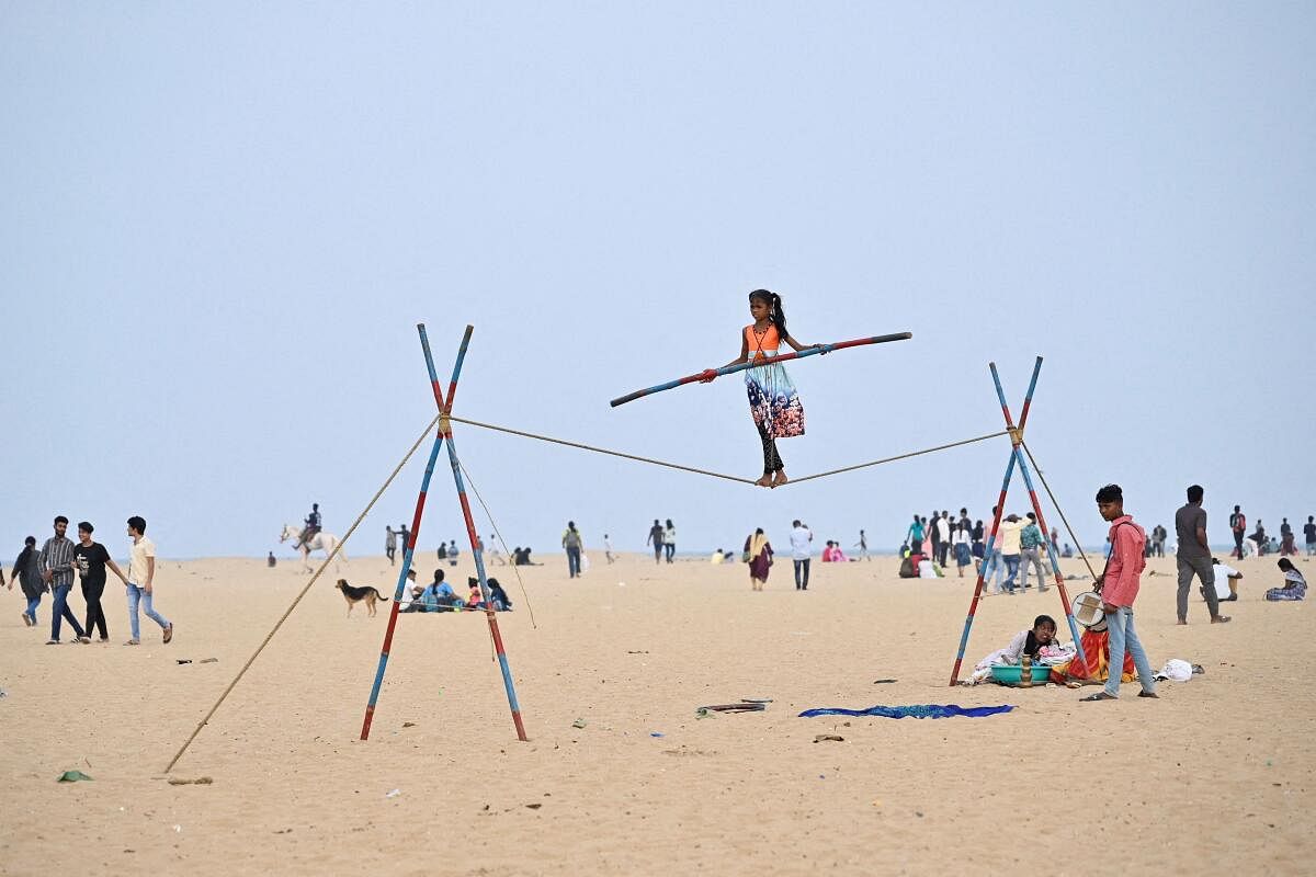 A girl walks on a tightrope to collect money by performing at Marina Beach in Chennai, India.