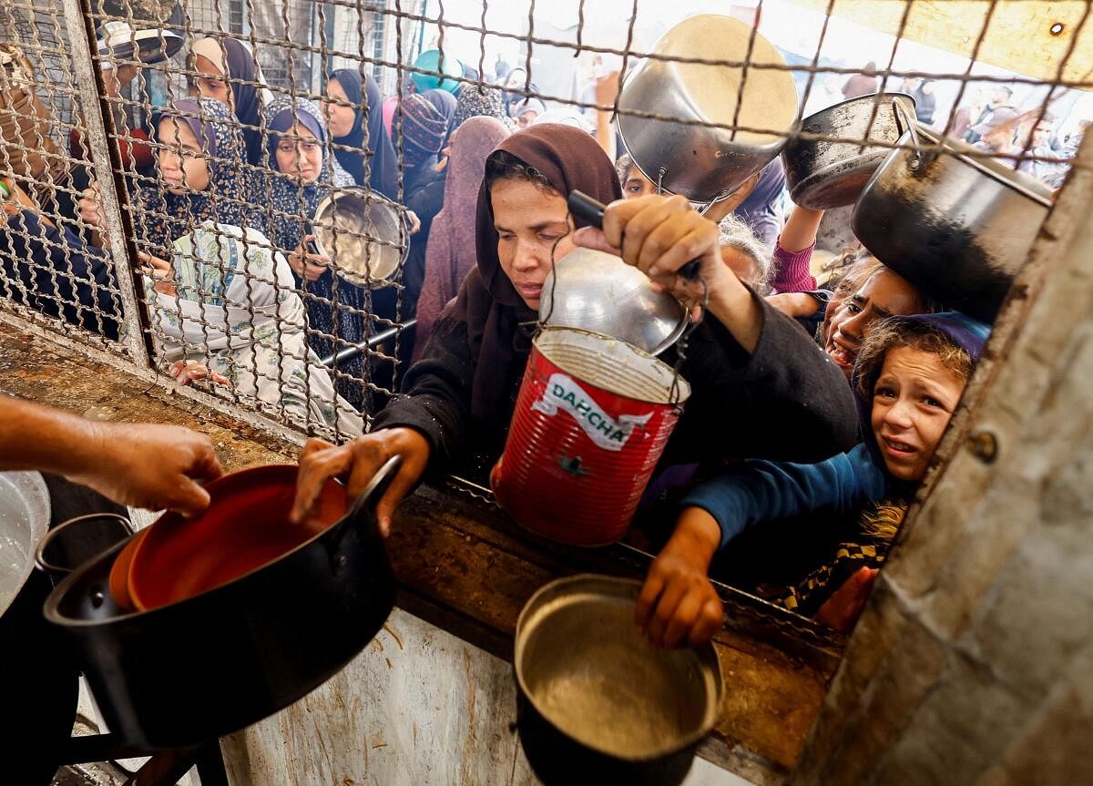 Palestinians gather to receive food cooked by a charity kitchen, amid a hunger crisis, as the Israel-Hamas conflict continues, in Khan Younis, southern Gaza Strip.