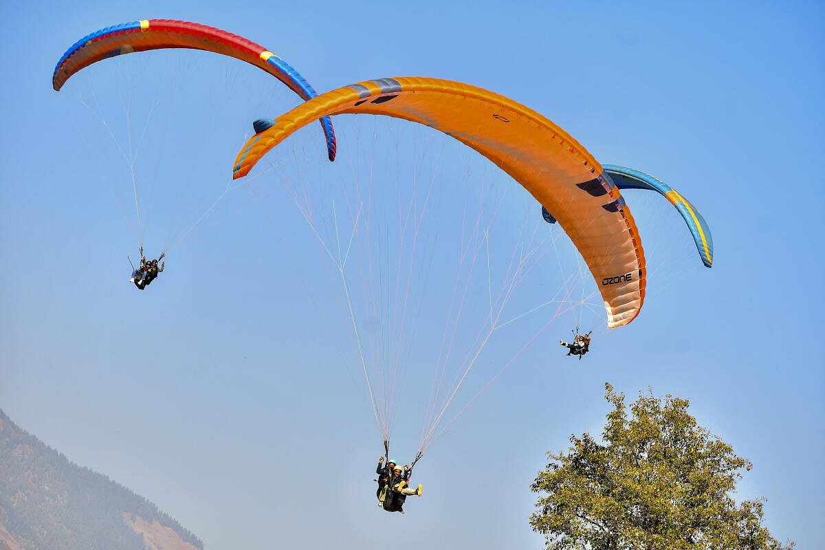 Tourists paraglide on a clear day, in Manali.