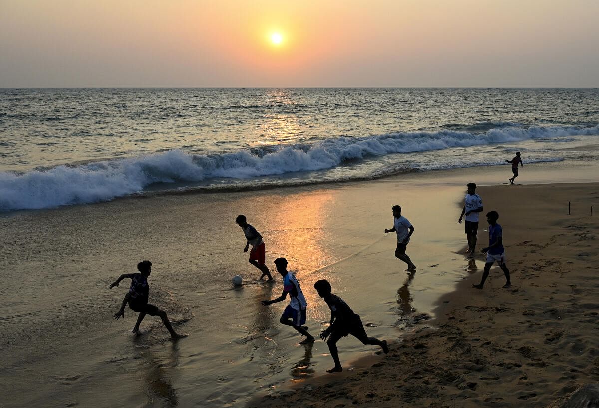 Youngsters play football at Poonthura Beach during sunset, in Thiruvananthapuram