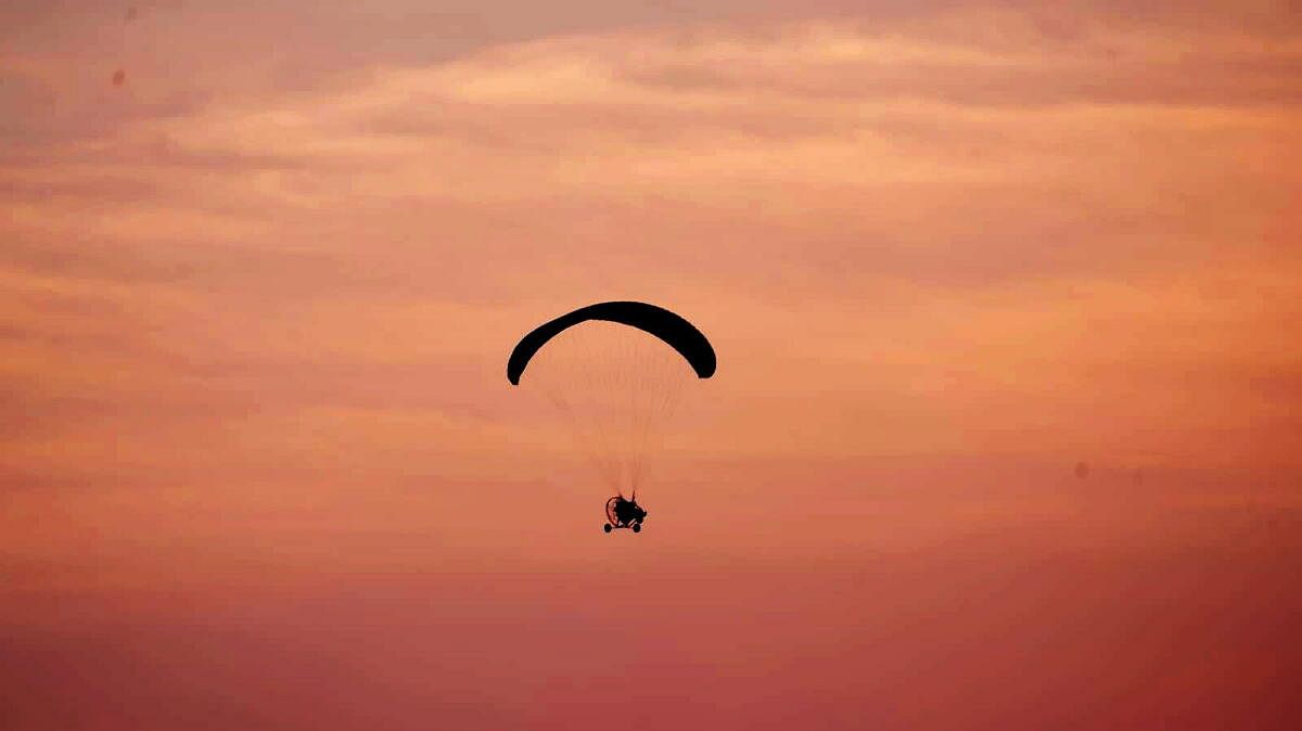 A tourist enjoys paragliding during 'Chitrakote Mahotsav' on the outskirts of Jagdalpur, in Bastar district, Chhattisgarh