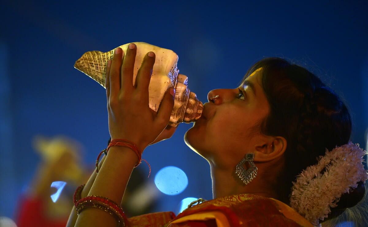 A 'Batuk kanya' or woman priest blows a conch shell during 'Ganga Aarti' at the ongoing Mahakumbh Mela, in Prayagraj, Uttar Pradesh