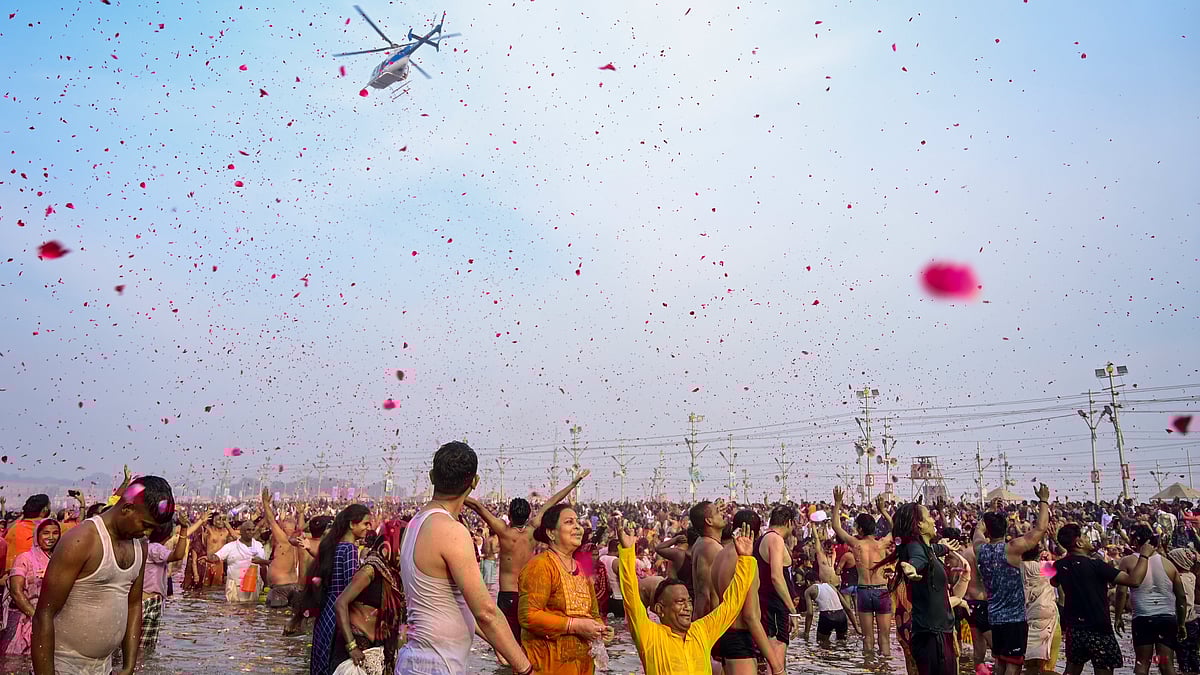 A helicopter showers flower petals on devotees taking holy dip at Sangam on the occasion of Maha Shivratri during the Maha Kumbh Mela 2025 in Prayagraj.