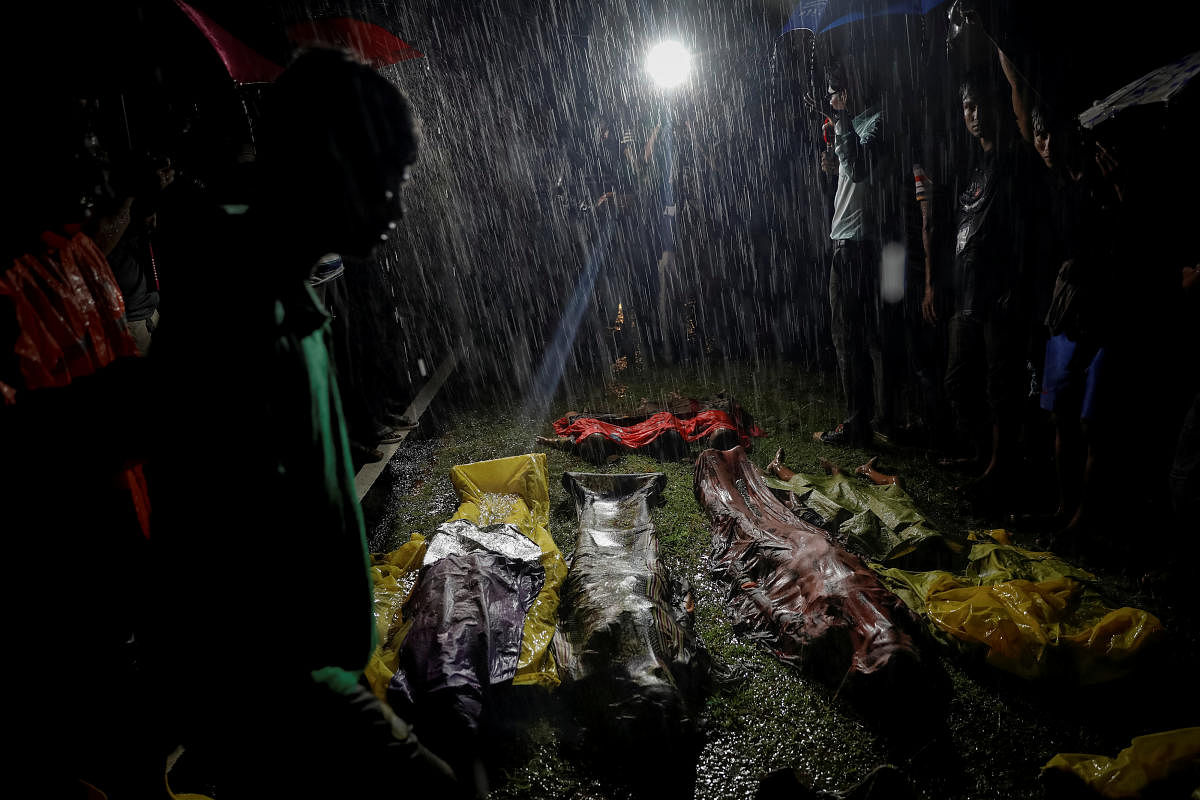 People gather under heavy rain around bodies of Rohingya refugees after the boat they were using to flee violence in Myanmar capsized off Inani Beach near Cox's Bazar, Bangladesh September 28, 2017. REUTERS/Damir Sagolj
