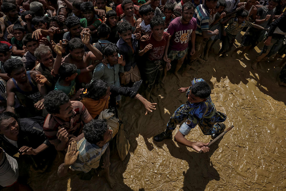 A security officer attempts to control Rohingya refugees waiting to receive aid in Cox's Bazar, Bangladesh, September 21, 2017. REUTERS/Cathal McNaughton