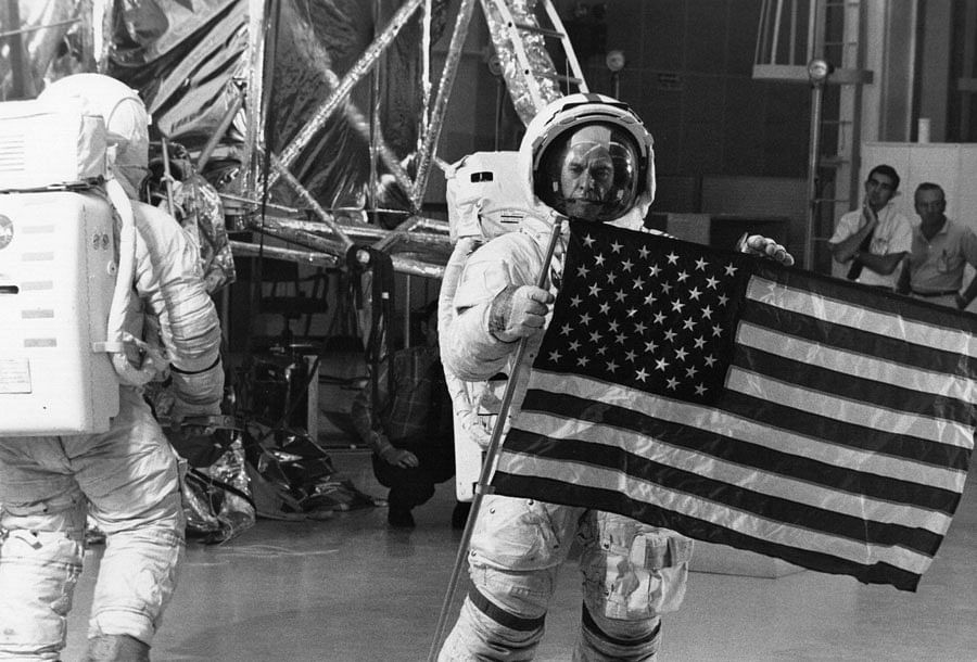 Ed Mitchell (left) goes toward the LM mockup while Al Shepard works with the telescoping crossbar at the top of the flag. (Photo by NASA)