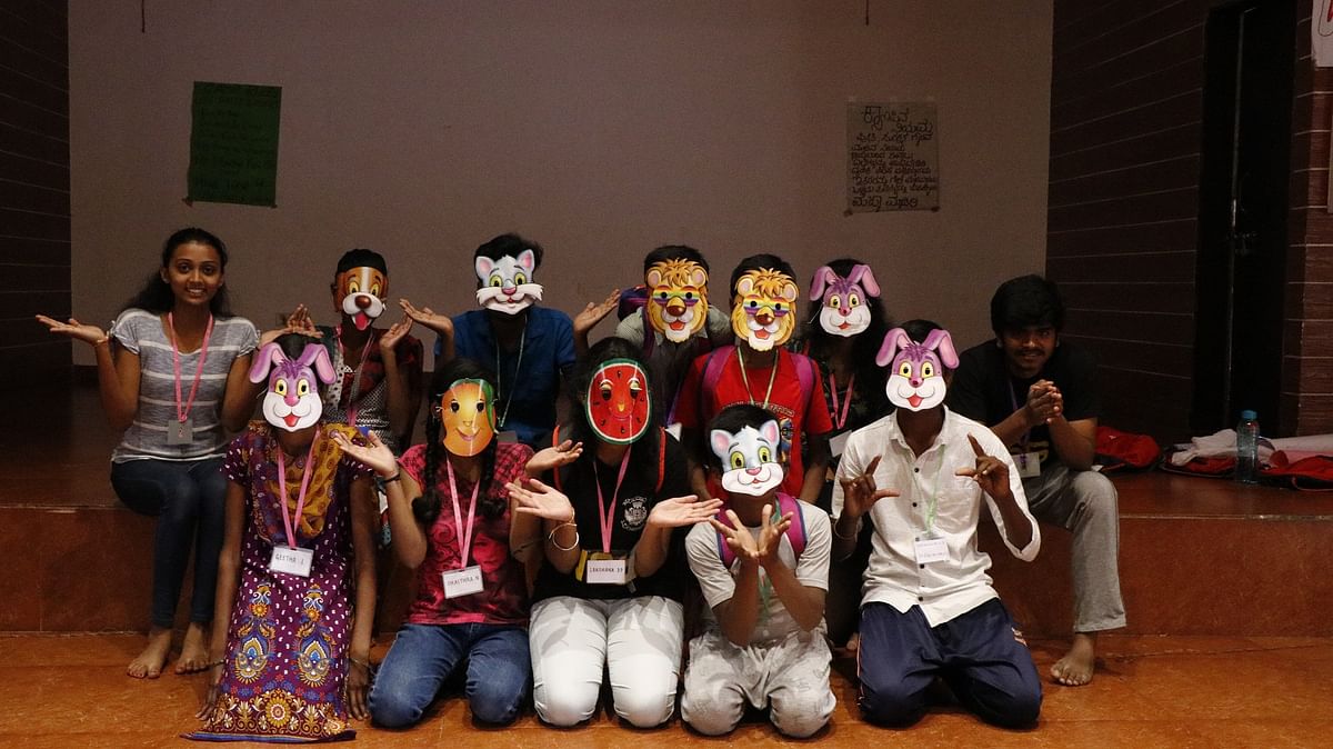 Children with volunteers wearing masks theymade at a camp hosted by Asha Foundation.
