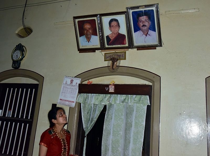 Anuradha, sister of murdered RTI activist Vinayak Baliga looks up at his portrait placed alongside the pictures of her deceased parents at her home in Kodialbail.