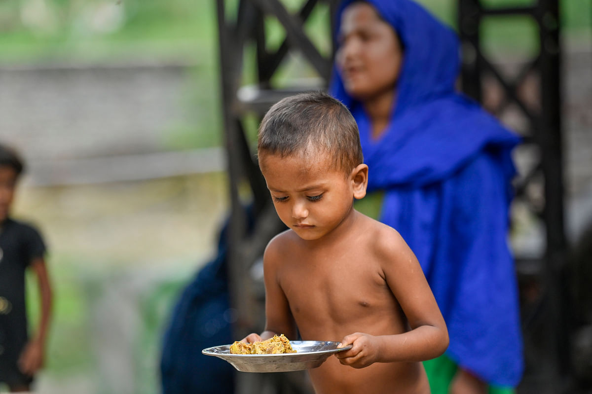 A boy holds a plate of food inside the Rohinya refugee settlement area in Kalindi Kunj, New Delhi. Credit: PTI File Photo