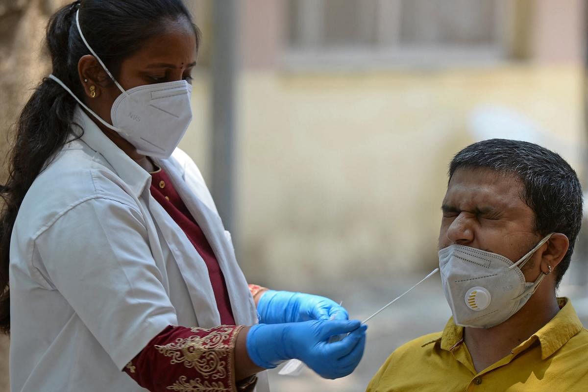 A medical worker takes a swab sample of a man for a Reverse Transcription Polymerase Chain Reaction (RT-PCR) test for the Covid-19 coronavirus screening at a testing centre in Hyderabad on April 29, 2021. Credit: AFP Photo