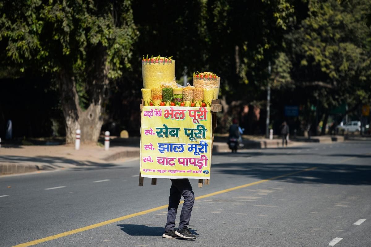 A traditional snack vendor balances his 'stall' on his head as he crosses a street near the India Gate in New Delhi. Credit: AFP Photo