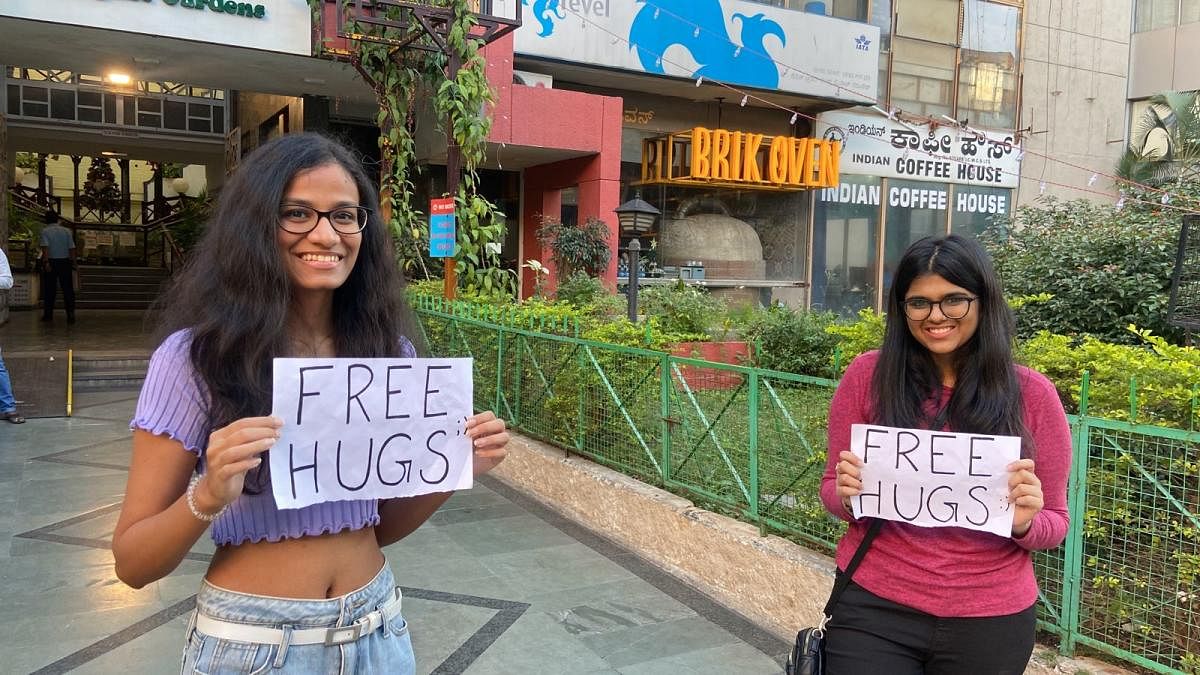 Two students offer hugs to Church Street visitors