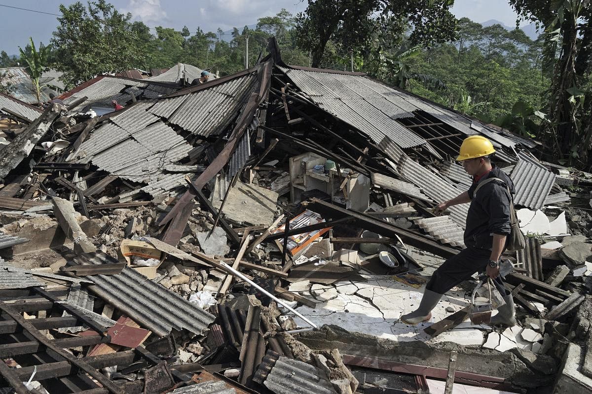 A rescuer walks on the rubble of houses in an area affected by an earthquake in Kalibening, Central Java, Indonesia, Thursday, April 19, 2018. The shallow earthquake in central Indonesia has killed people and damaged hundreds of homes, disaster officials said Thursday as they declared a two-week emergency for the affected areas. AP/PTI