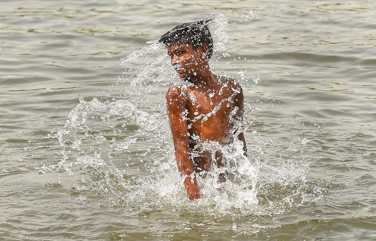 A child takes a dip in a pond on a hot sunny day to cool himself from the scorching heat in Lucknow on Thursday. PTI