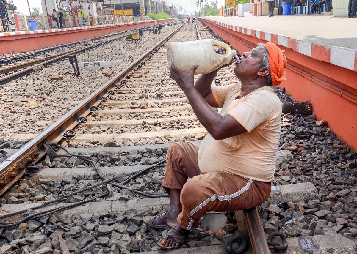 A worker drinks water from a big plastic jar on a hot sunny day at Barnagar railway station in Kolkata on Friday. PTI Photo