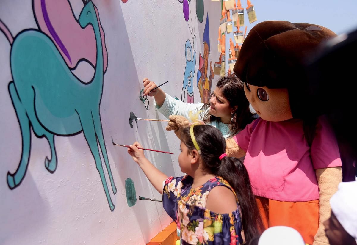 BJP leader Poonam Mahajan, Nicktoon Dora and and kids paint a wall as part of a campaign to beautify the city, in Mumbai on Saturday. PTI Photo