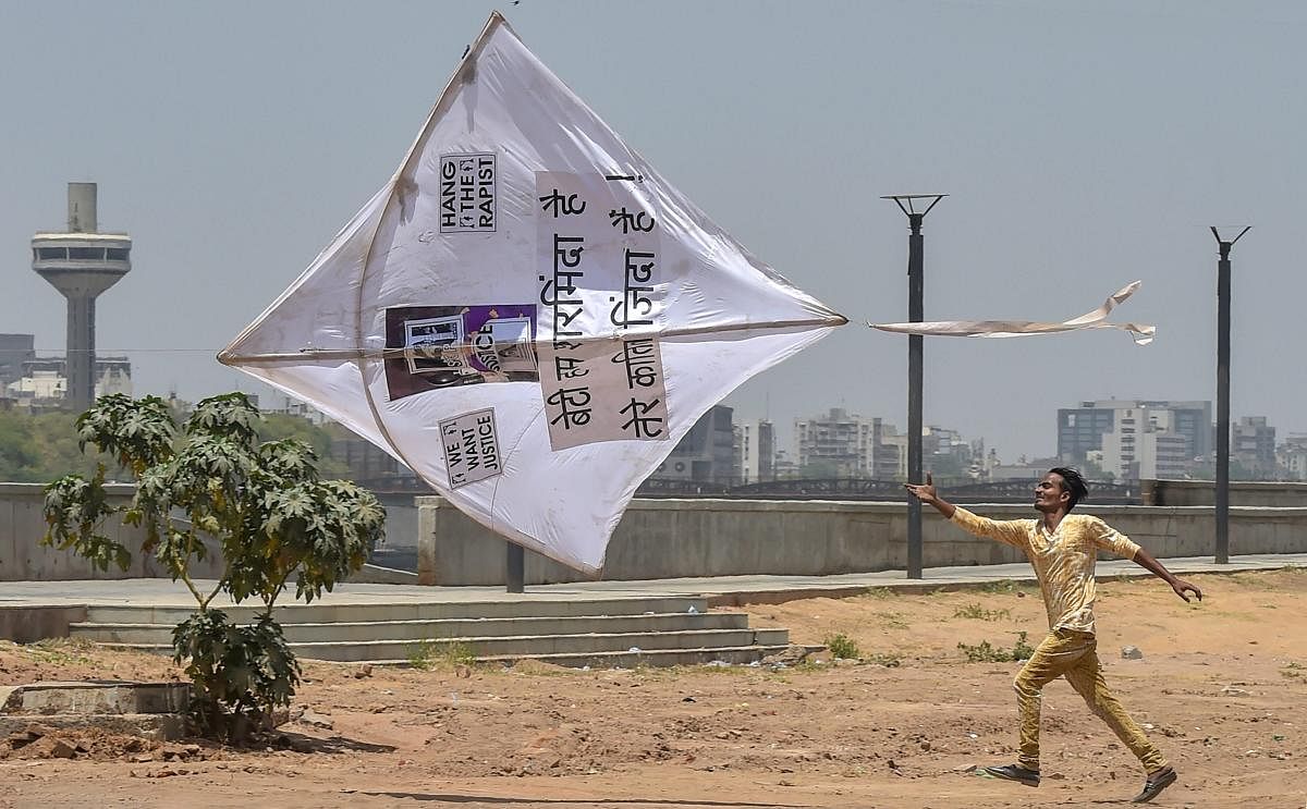 A man runs after a kite during a protest against the recent rape and murder of an eight-year-old Kathua girl, an Unnao teenager and an eleven-year-old Surat girl, in Ahmedabad on Sunday. PTI Photo