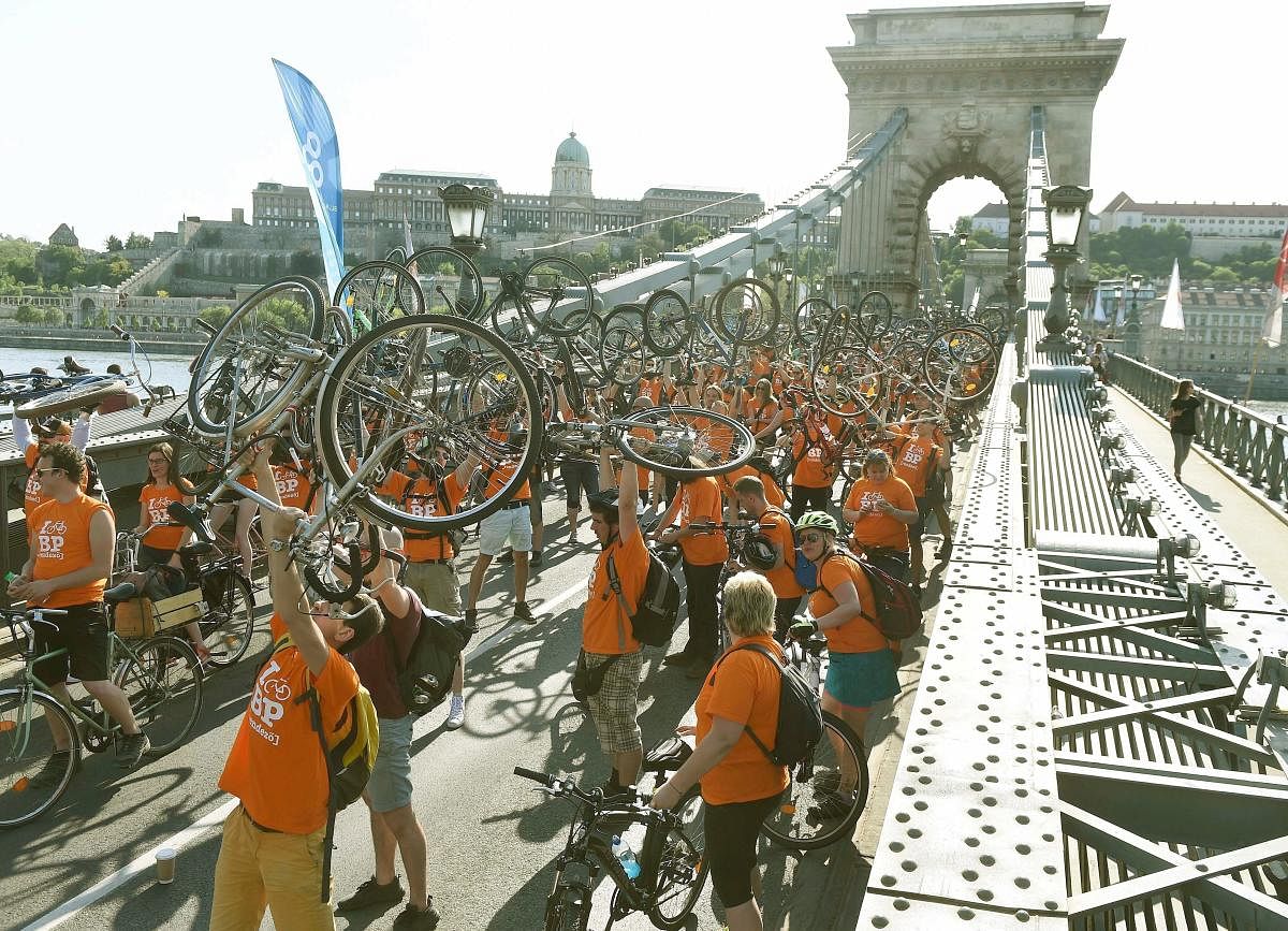 Cyclists raise their bikes on Chain Bridge across River Danube with the Royal Palace in the background during a march called I Bike Budapest in Budapest, Hungary. AP/PTI Photo