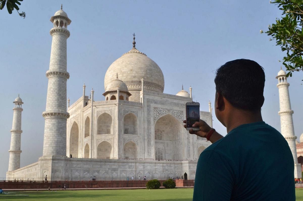 A man clicks picture of Taj Mahal in Agra on Tuesday. The Supreme Court on Tuesday expressed concern over the change of colour of the iconic Taj Mahal which had become yellowish earlier and was now turning brown and green. PTI Photo