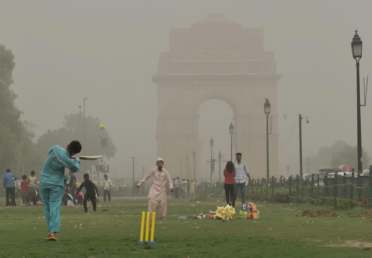 Children play cricket as the weather changes during a after dust storm in New Delhi on Wednesday. PTI Photo