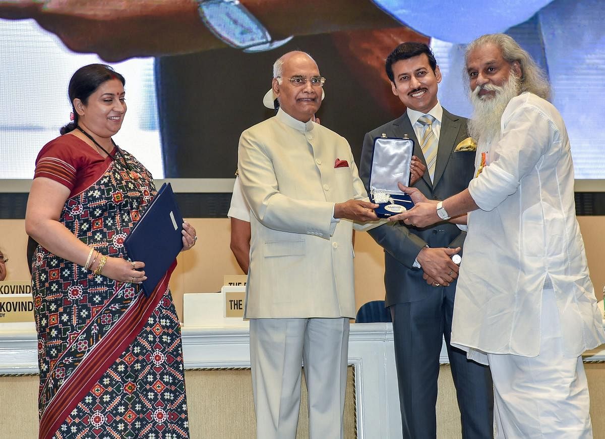 President Ram Nath Kovind confers Best Playback Singer Award on K J Yesudas during the 65th National Film Awards function at Vigyan Bhavan in New Delhi on Thursday. I & B Minister Smriti Irani and MoS for I & B Rajyavardhan Rathore are also seen. PTI Photo