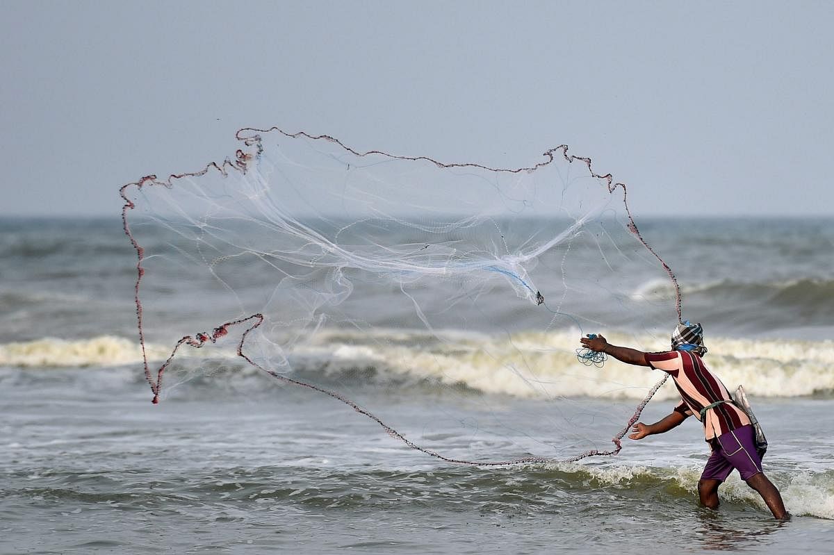 A fisherman throws a net for fishing at Marina Beach in Chennai on Saturday. PTI