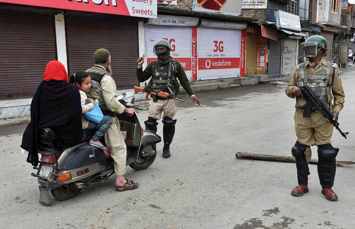 A security personnel stops a scootrist during curfew-like restrictions imposed to maintain law and order in Srinagar on Monday. A strike call was given by the separatists over the recent killings of civilian. PTI
