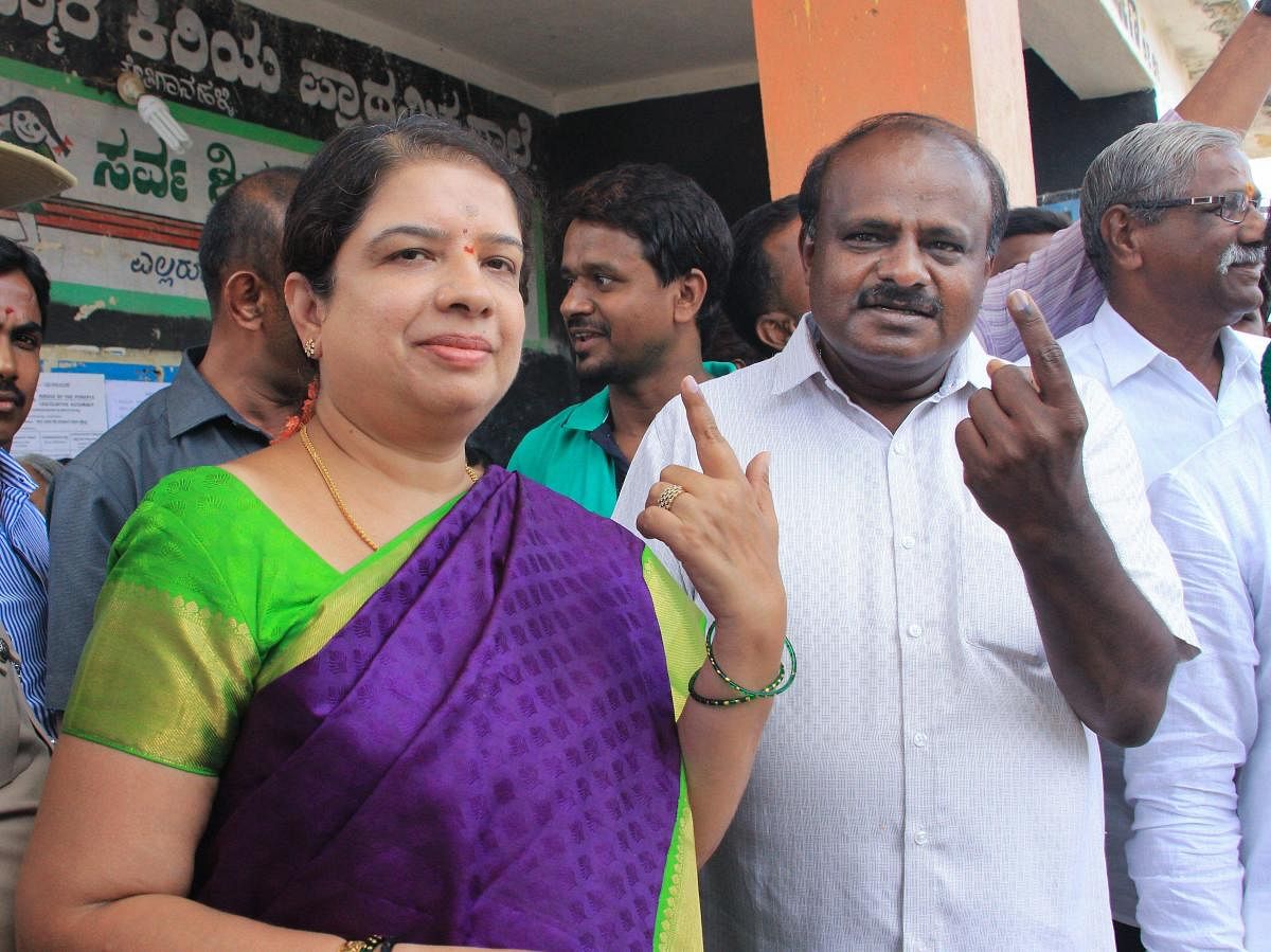 JD(S) State President H D Kumaraswamy and his wife Anitha Kumaraswamy show their inked fingers after casting their votes for the Karnataka Assembly elections in Ramnagar, Karnataka on Saturday. PTI Photo