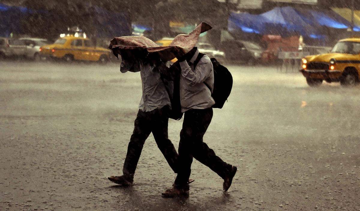 Two men use a plastic sheet to protect themselves, as it rains in Kolkata on Sunday. PTI Photo
