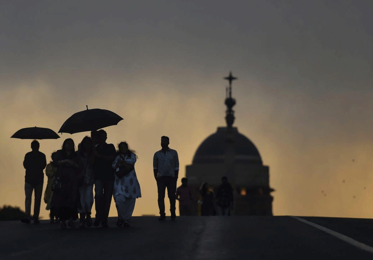 People are seen silhouetted as they enjoy the pleasant weather before after rains, at Raisina Hills in New Delhi on Sunday. PTI Photo