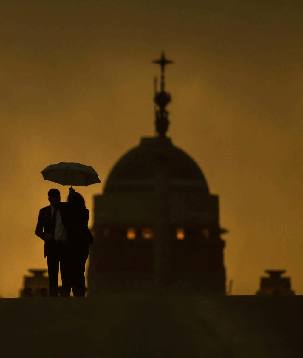 People are seen silhouetted as they enjoy the pleasant weather before after rains, at Raisina Hills in New Delhi on Sunday. PTI Photo