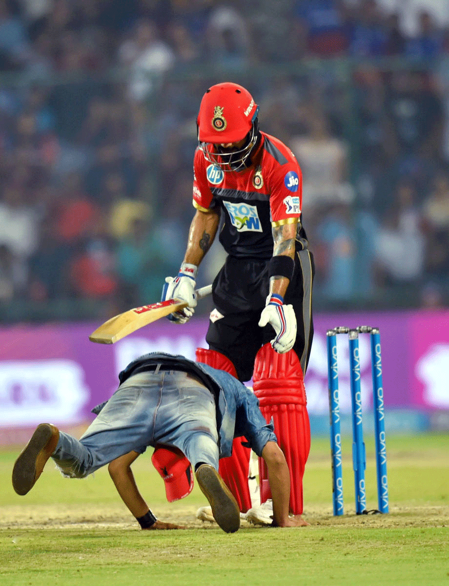 A cricket fan enter the ground and seeking blessing from Royal Challengers Bangalore captain Virat Kholi during their IPL 2018 cricket match against Delhi Daredevils' at Ferozshah Kotla in New Delhi on Saturday. PTI Photo