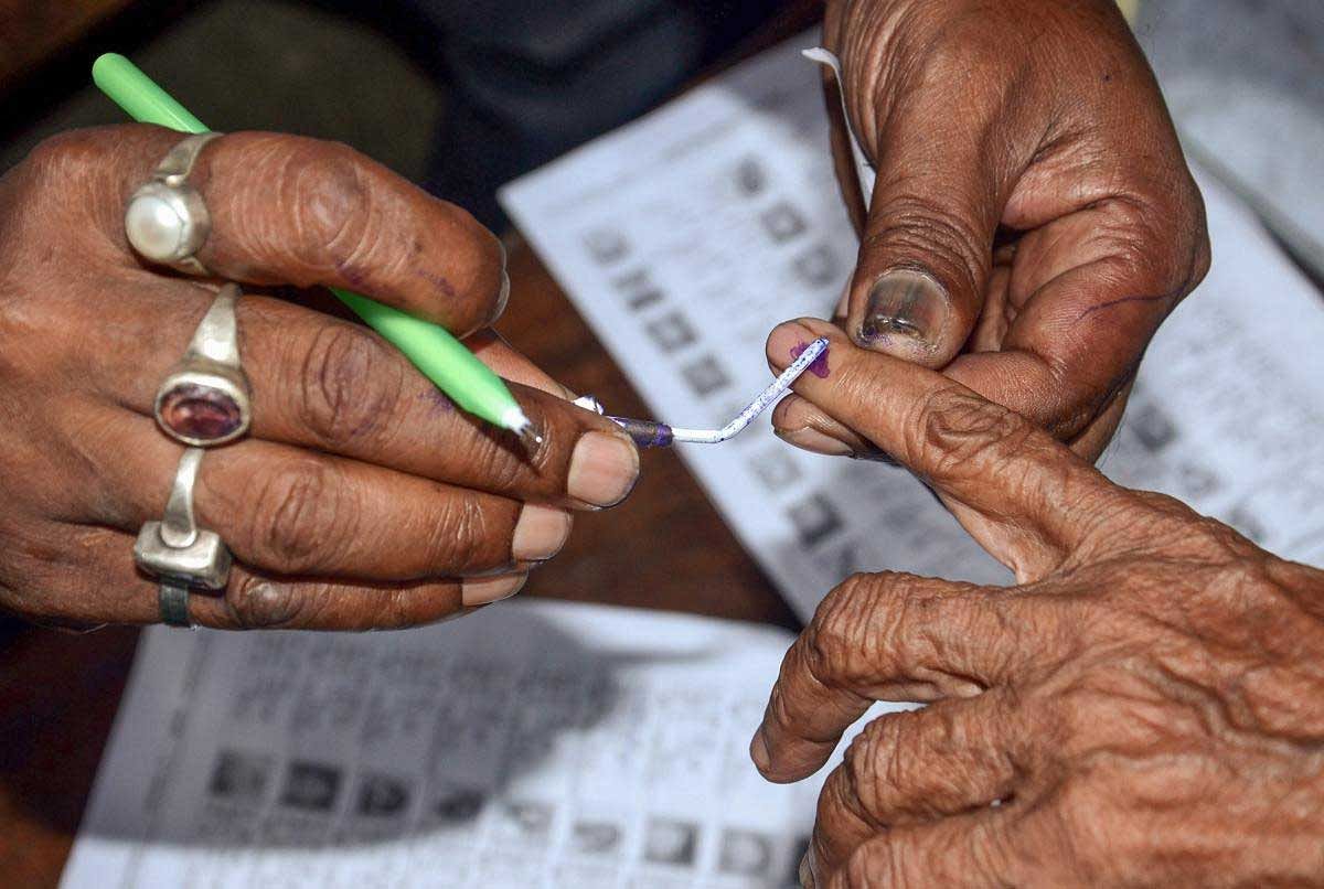 Polling officials put an ink mark on a voter's finger after during Panchayat Election at a polling booth in Howrah district of West Bengal on Monday. PTI Photo
