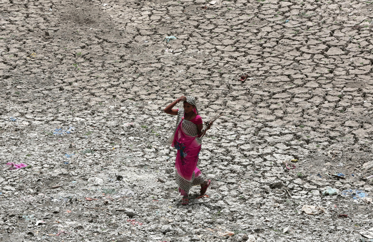 A women carries firewood as she walks through a dried-up portion of the Sabarmati river on a hot summer day in Ahmedabad, India, May 16, 2018. REUTERS