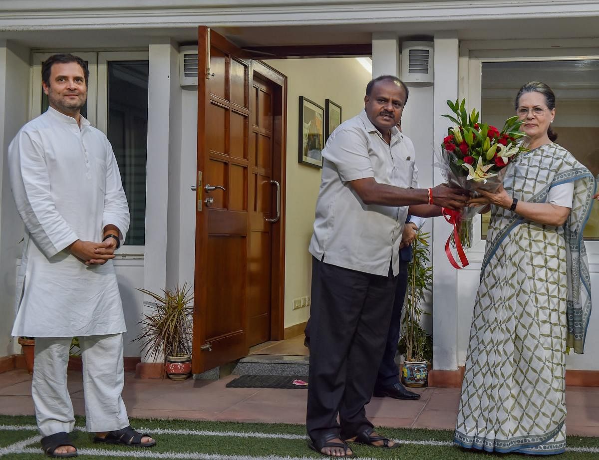 JD(S) leader and Karnataka chief minister-designate H D Kumaraswamy presents a bouquet to former Congress president Sonia Gandhi as Congress President Rahul Gandhi looks on during a meeting, at the latter's residence, in New Delhi. PTI Photo